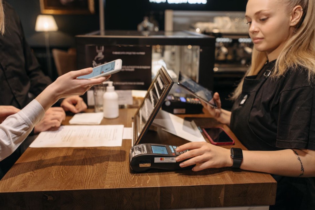 A staff member taking a contactless card payment at a café counter